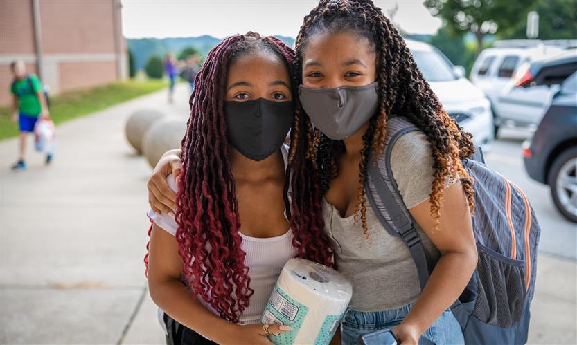 Two girls smile while wearing masks
